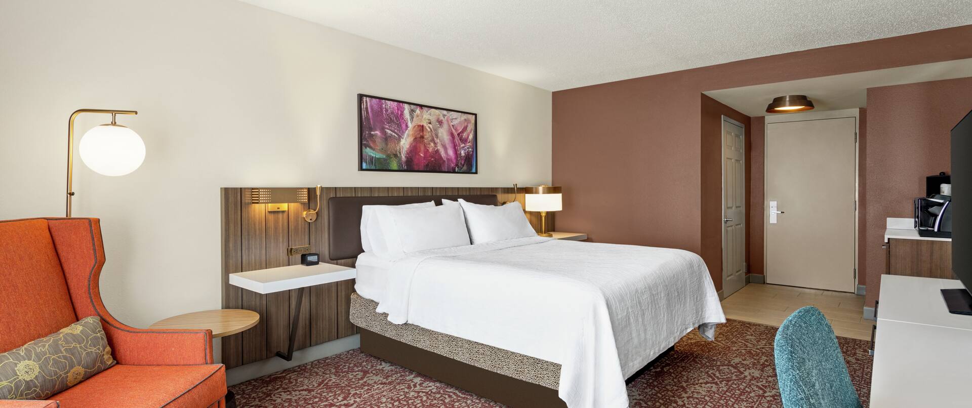 Spacious guest room featuring comfortable king bed, work desk, and TV.