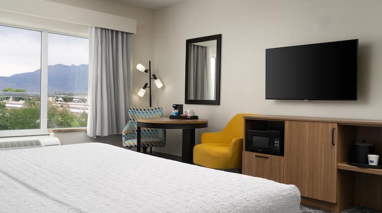 King Guest Bedroom with Bed, Work Desk, Two Chairs, Floor Lamp, Mini Microwave, and TV