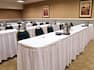 Classroom Setup in Meeting Room With Water Pitchers, Notepads, and Chairs at Tables With White Linens