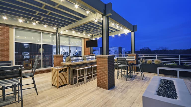 Outdoor Patio at Night with Fire Pit, Grills, Tables and Chairs