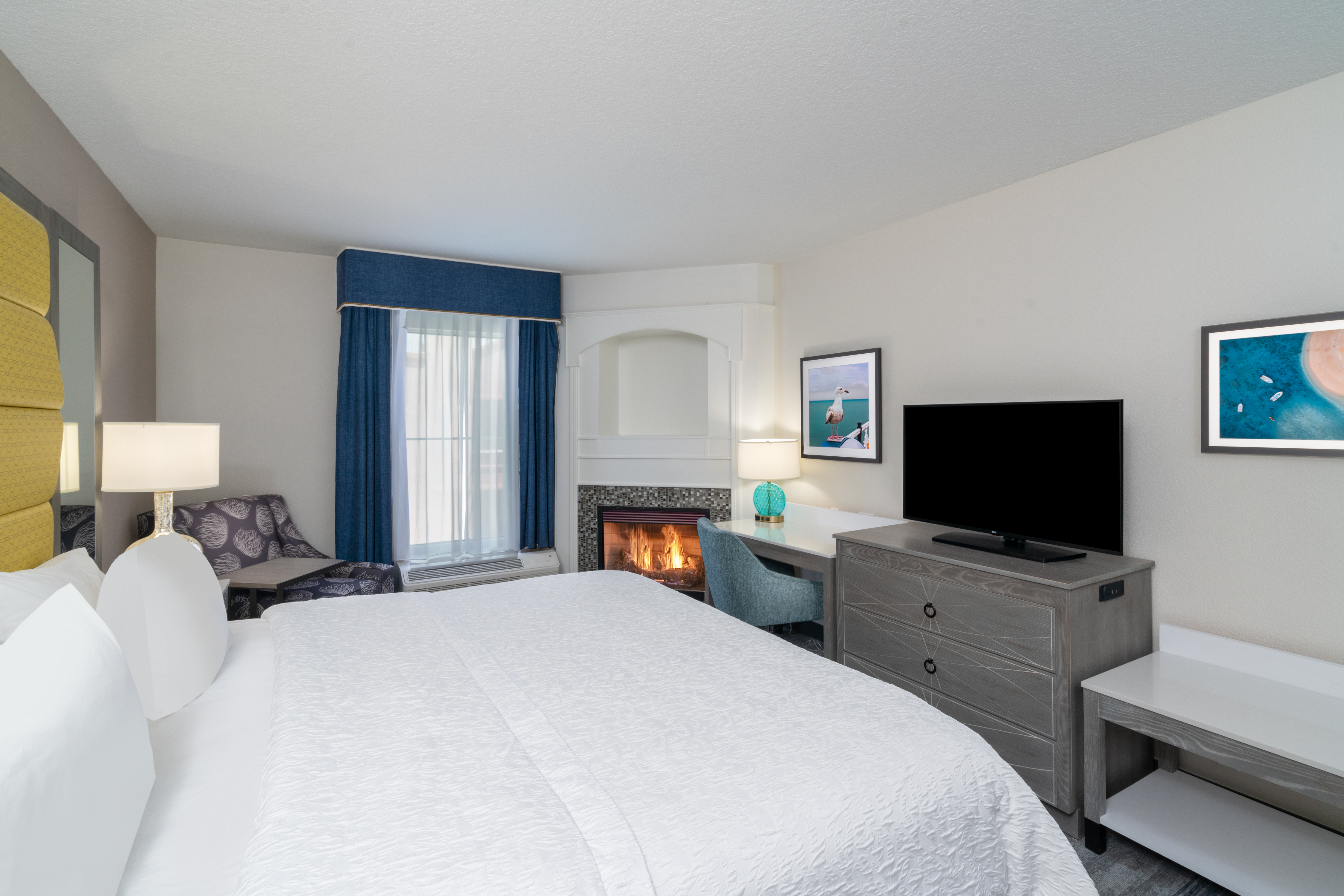 Guest Room with Large Bed Fireplace Armchair Desk and HDTV
