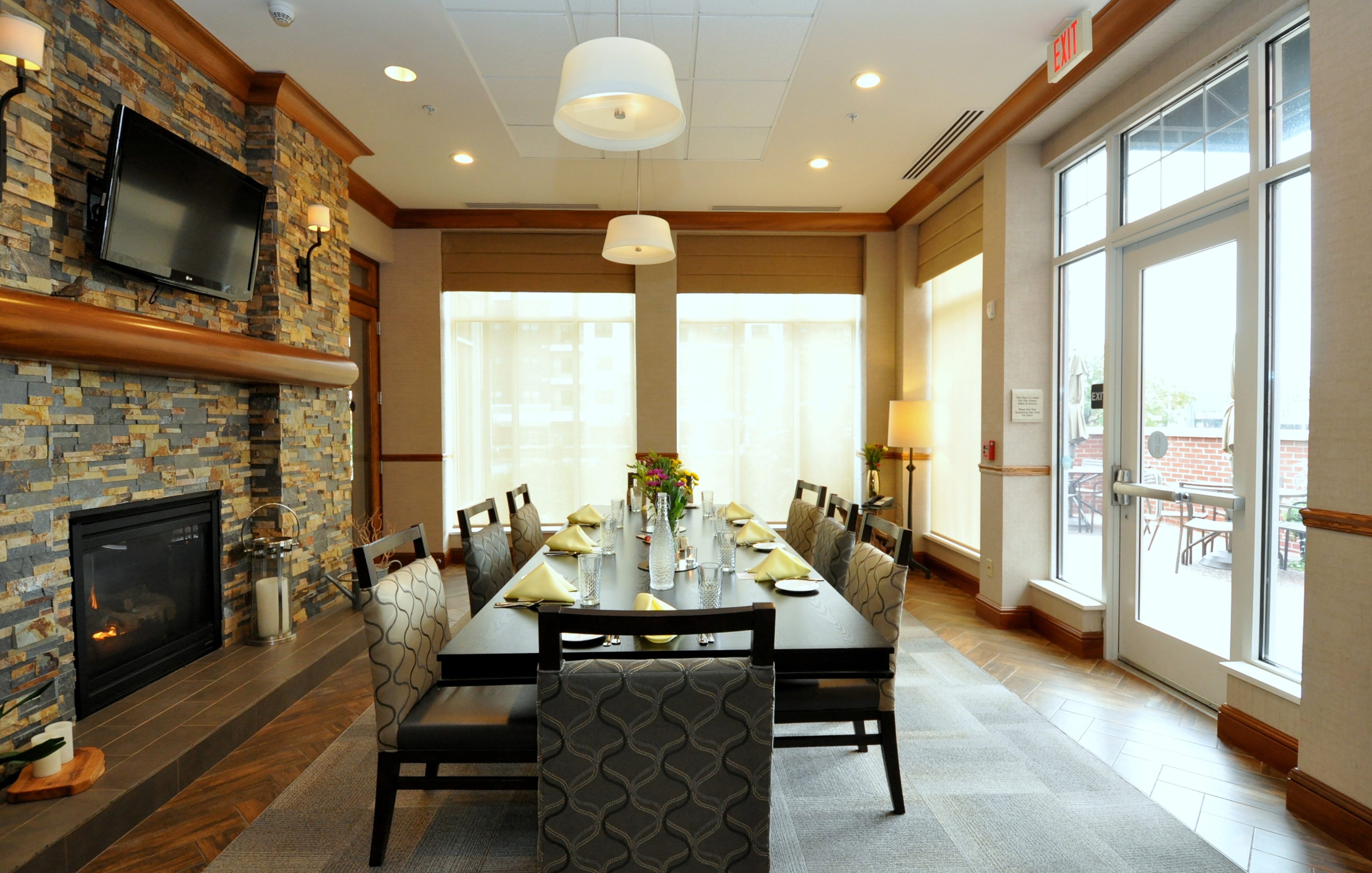 A Large Table next to a Fireplace and HDTV in the Lobby with Large Windows