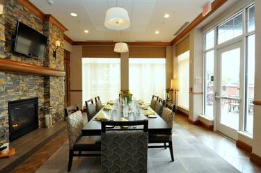 A Large Table next to a Fireplace and HDTV in the Lobby with Large Windows