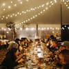 Group of people sitting down to a meal at long table, with lights overhead