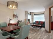 Spacious premium guestroom living area featuring dining table, work desk, and sofa. 
