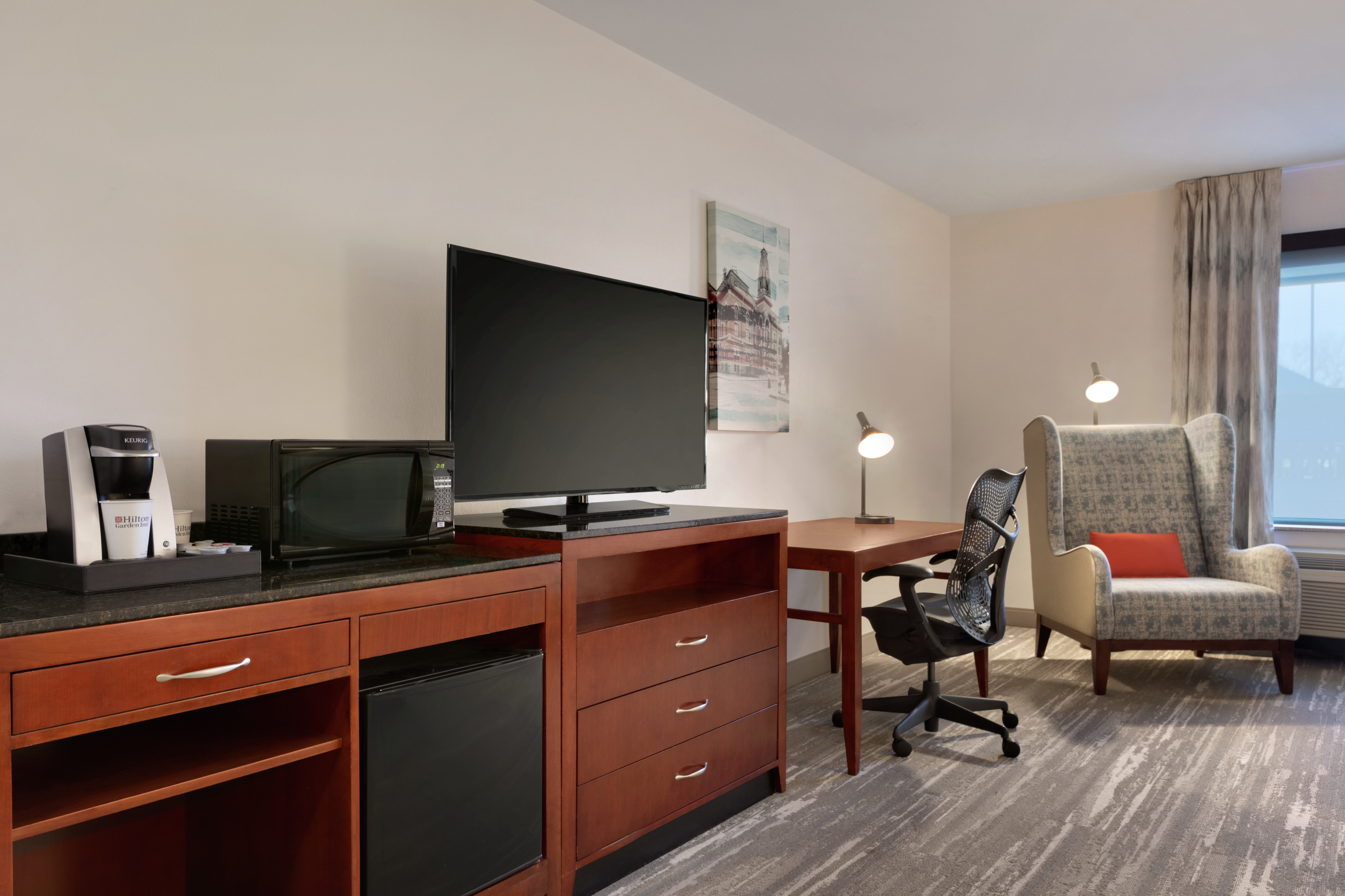 Spacious premium guestroom featuring convenient mini-fridge, TV, and work desk desk with ergonomic chair.