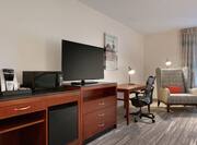 Spacious premium guestroom featuring convenient mini-fridge, TV, and work desk desk with ergonomic chair.