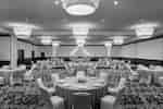 Spacious hotel ballroom featuring banquet setup with beautiful linens and candle-lit centerpieces.