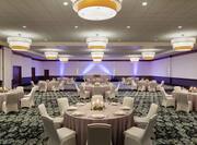 Spacious hotel ballroom featuring banquet setup with beautiful linens and candle-lit centerpieces.