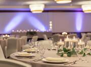 Spacious ballroom featuring banquet setup with beautiful cande-lit centerpiece.