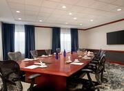 Spacious hotel boardroom featuring large table with ample seating and TV for presentations.
