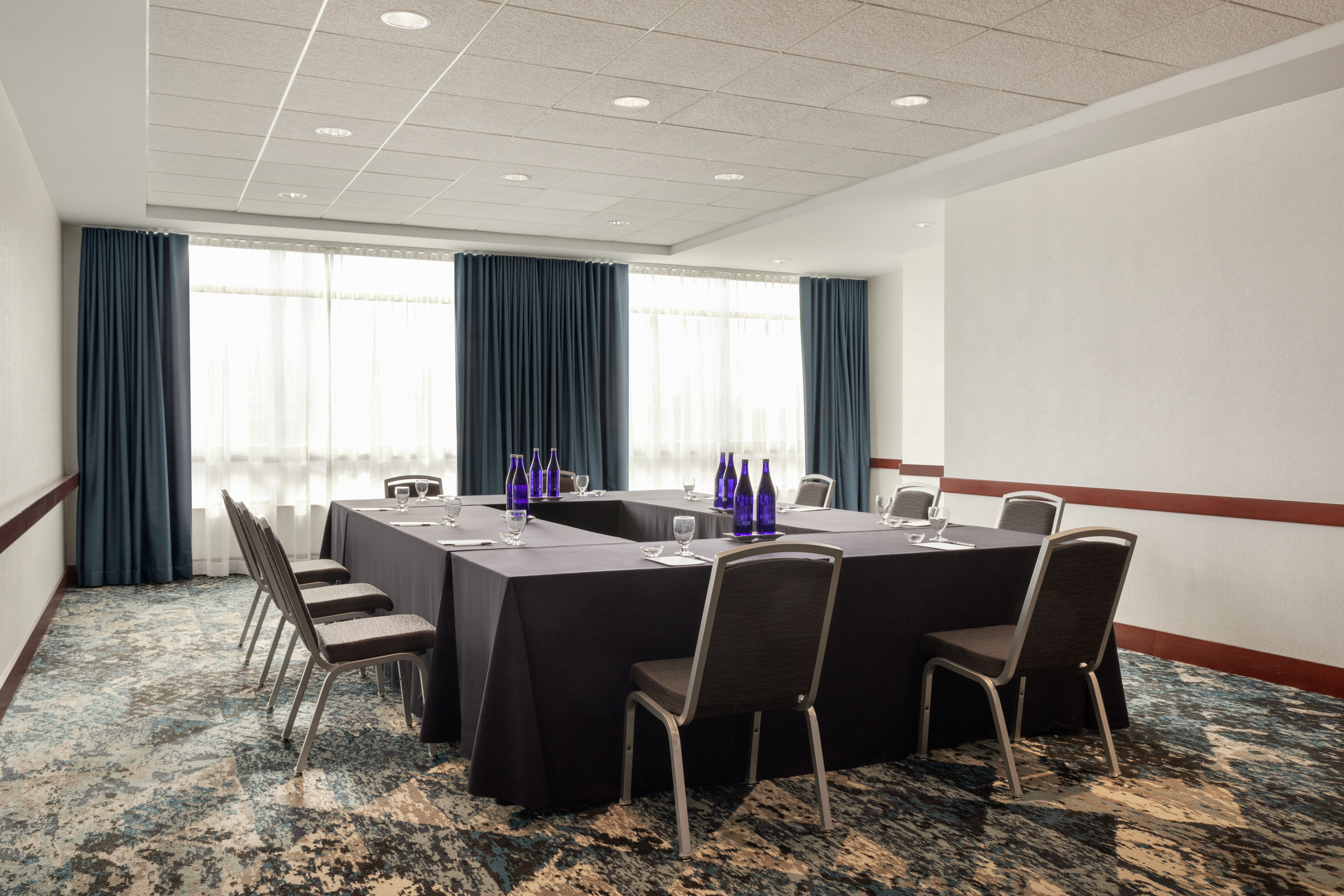 Bright hotel meeting room featuring large windows and hollow square table setup.