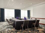 Bright hotel meeting room featuring large windows and hollow square table setup.