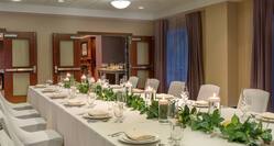 Spacious hotel event space foyer featuring large dining table set with beautiful centerpiece.