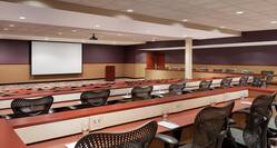 Spacious hotel amphitheater featuring a classroom setup with ample seating, podium, and projector screen at front of room.