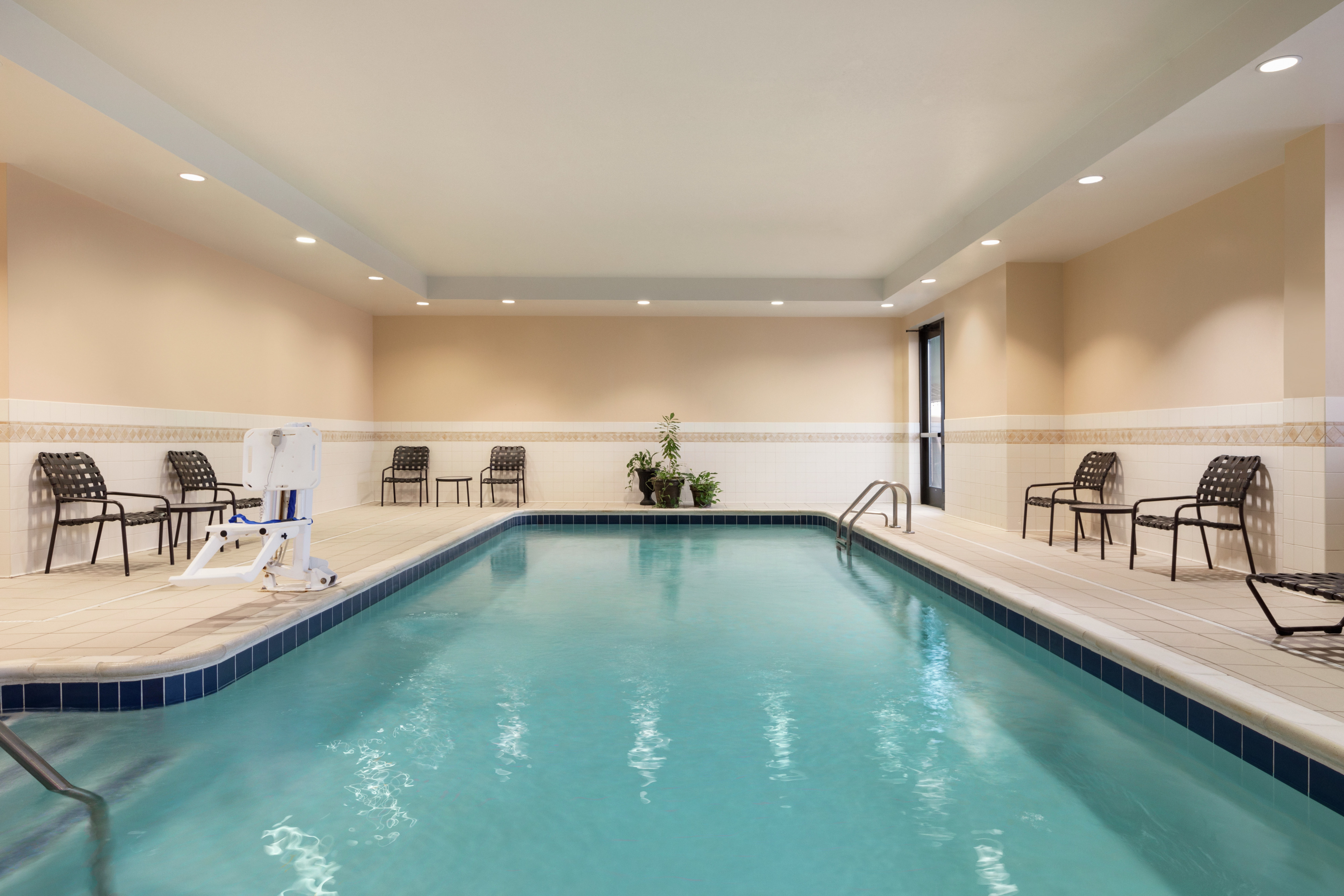 Large indoor swimming pool featuring ample seating, bright lighting, and accessible chair lift.
