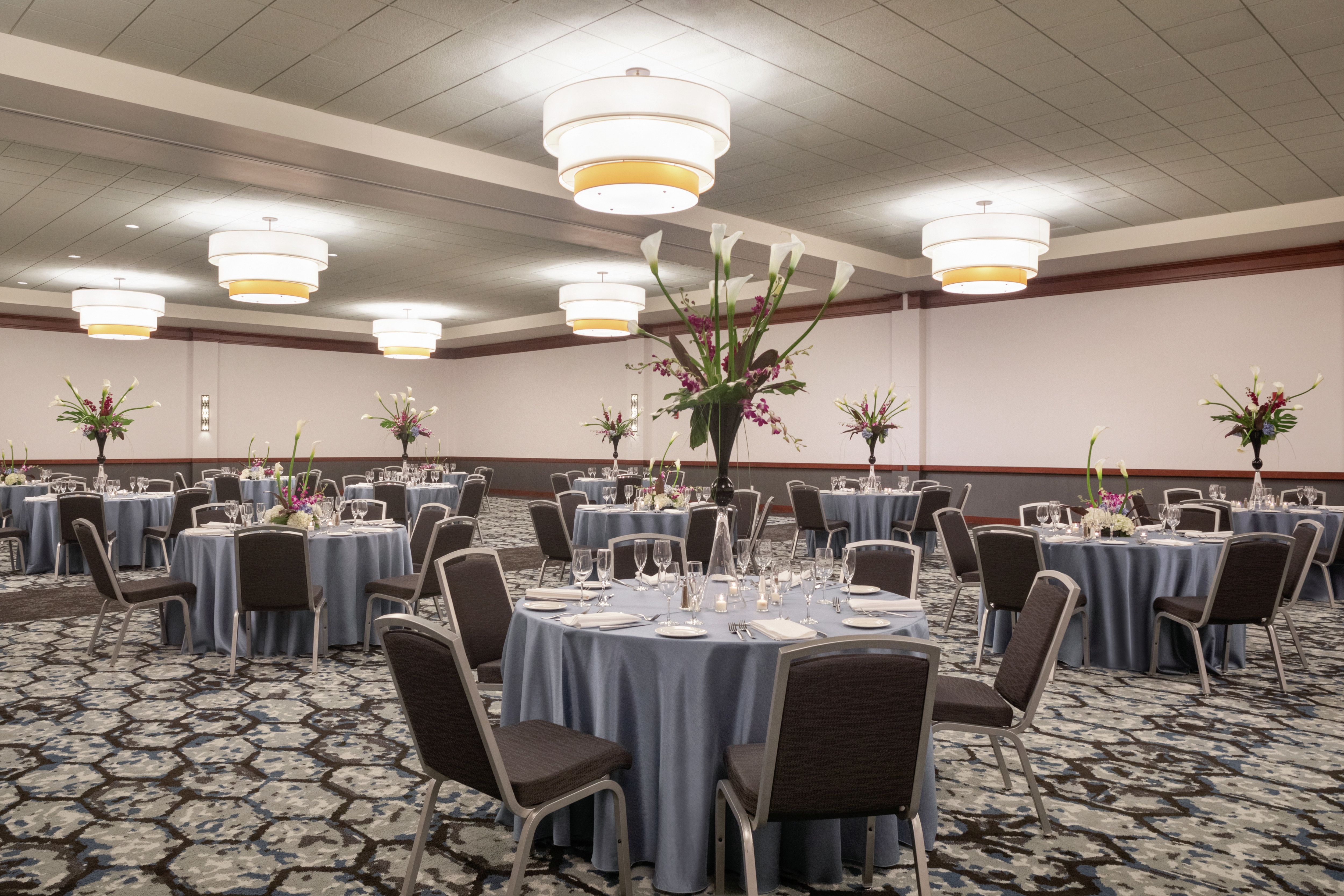 Spacious hotel banquet facility featuring ample seating, large tables, and stunning centerpieces.