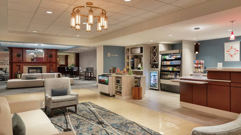 Spacious hotel lobby featuring comfortable seating area, front desk, and convenient snack shop.