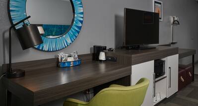 Desk with Round Mirror and HDTV in Guest Room