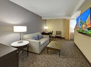 Guest Suite Lounge Area with Sofa, Coffee Table, Work Desk, Armchair and Wall Mounted HDTV