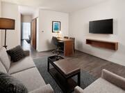 Guest Suite Lounge Area with Wall Mounted HDTV, Work Desk, Sofa, Armchair and Coffee Table