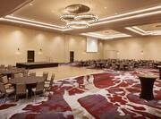 Spacious Ballroom Area with Round Tables, Chairs and Stage Area