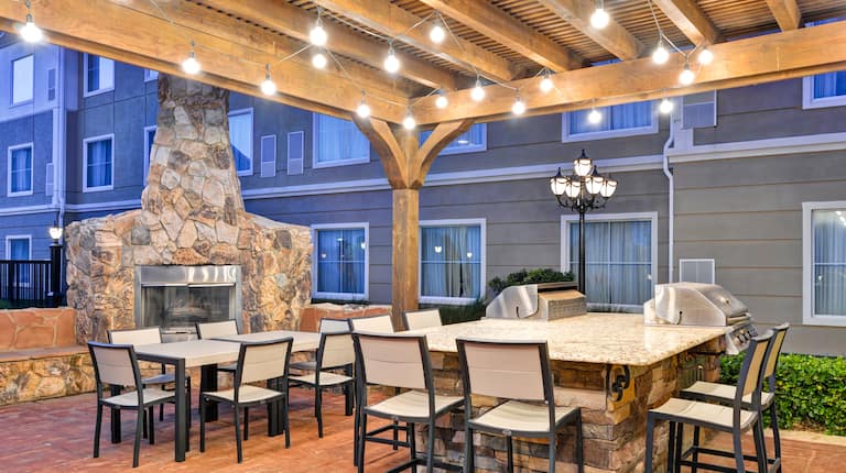 Covered Patio Area with Two BBQ Grills, a Fireplace, Tables, and Chairs