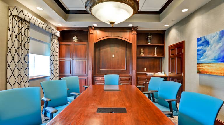 Boardroom-Style Setup with Seven Teal Chairs Around a Long Table in a Meeting Room