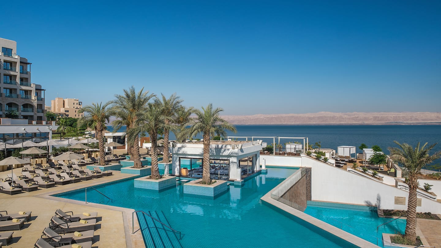 a swimming pool with palm trees and a building with a body of water