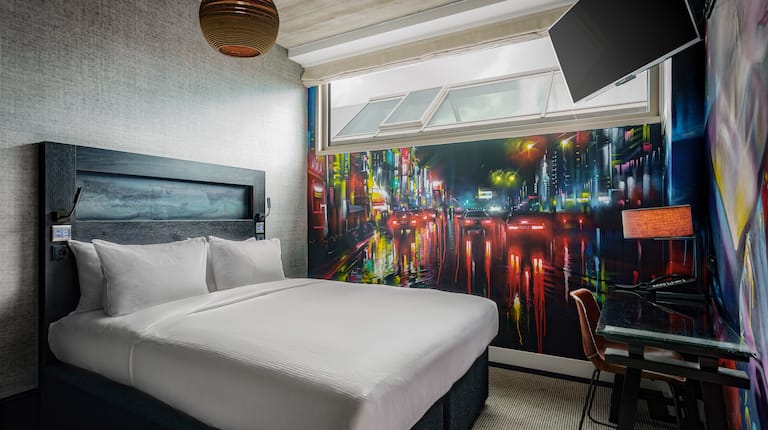 Kamer met queensize bed met hd-tv, bureaugedeelte en kleurrijke muurschildering