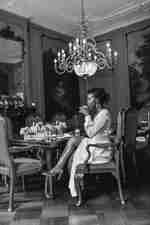 身穿白色連身裙的女士在喝咖啡