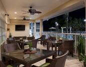 Outside Dining on Illuminated Restaurant Porch With TV and Ceiling Fans at Night