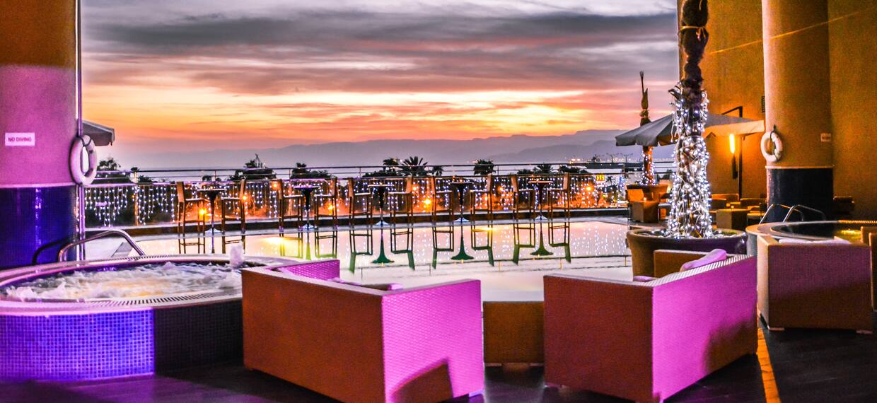 Infinity Chill Out Area With Lounge Seating by Hot Tub Illuminated in Pink Lights at Sunset