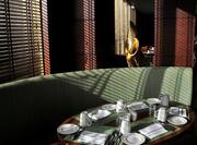 Detailed View of Place Settings on Oval Table by Window and Green Booth and Two Brown Chairs in Gusto Resaturant