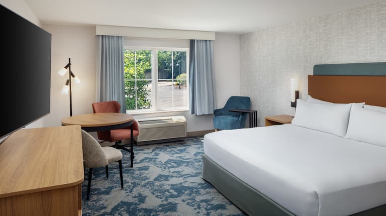 Large Bed, Armchair, TV and Seating Area in a Guest Room