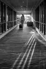 Гост на хотела, който се разхожда през осветения от слънцето коридор