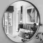 سرير مزدوج ينعكس على المرآة المستديرة في غرفة النزلاء