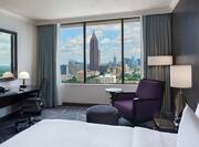 Guest Room with Large Bed Desk Armchair and City View