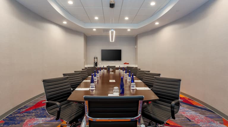 TV and Boardroom Table Surrounded by Black Chairs in Meeting Space