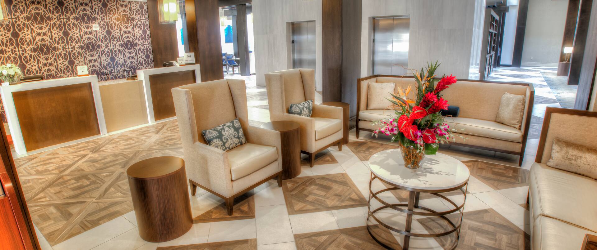 Overview of Brightly Lit Lounge Seating in Lobby, Front Desk, and Elevator Bay