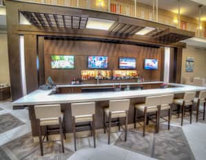 Fully Stocked Lobby Bar With Four TVs and Counter Seating