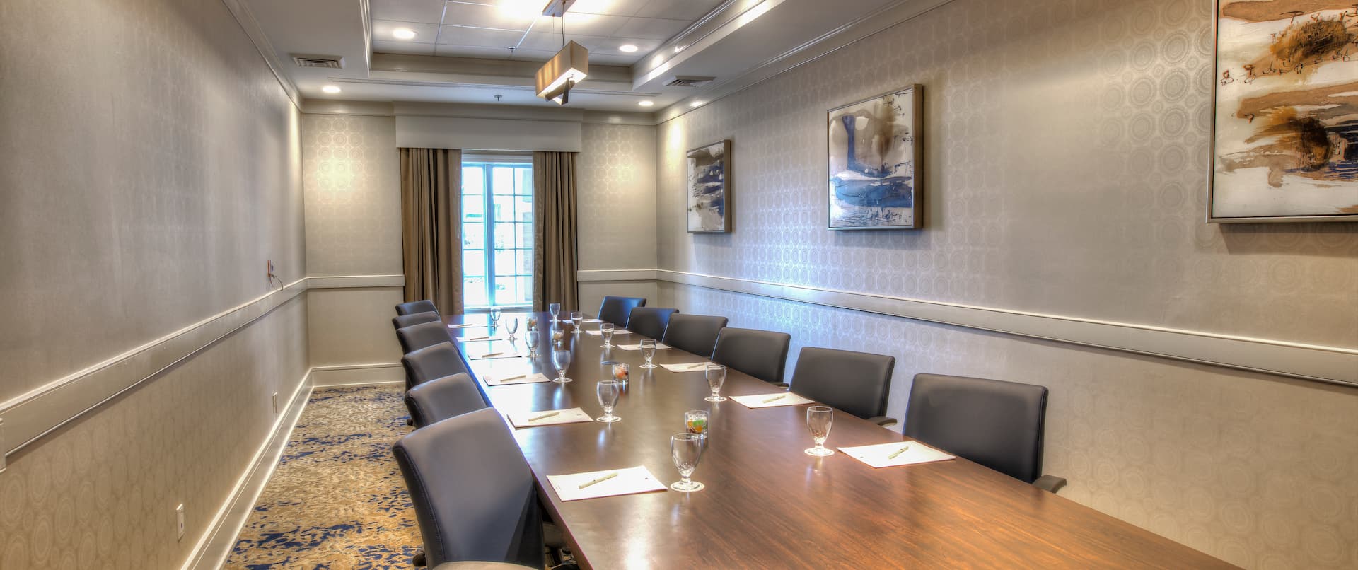 Black Chairs Around Long Table in Boardroom With Window and Wall Art