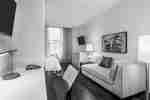TV Above Work Desk, View of Queen Bed, Window WIth Sheer Drapes, TV, Illuminated Lamps and Chaise Lounger in Studio