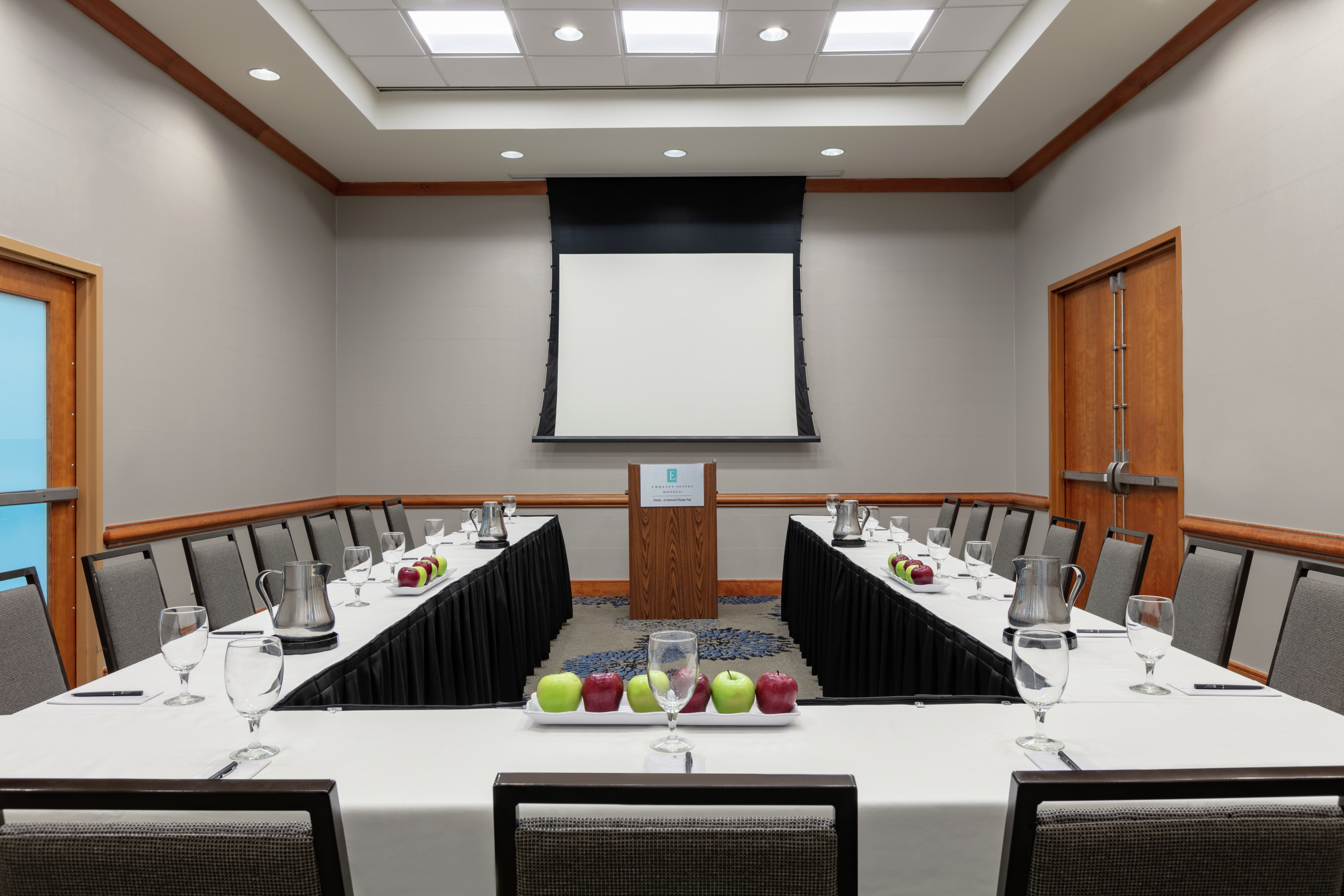 Spacious meeting room facility featuring high ceilings, u shape table setup, and podium.