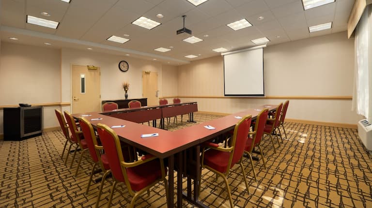 Meeting room with tables and chairs in U-shaped setup.