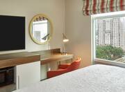 a bed, tv and desk in a room with a city view