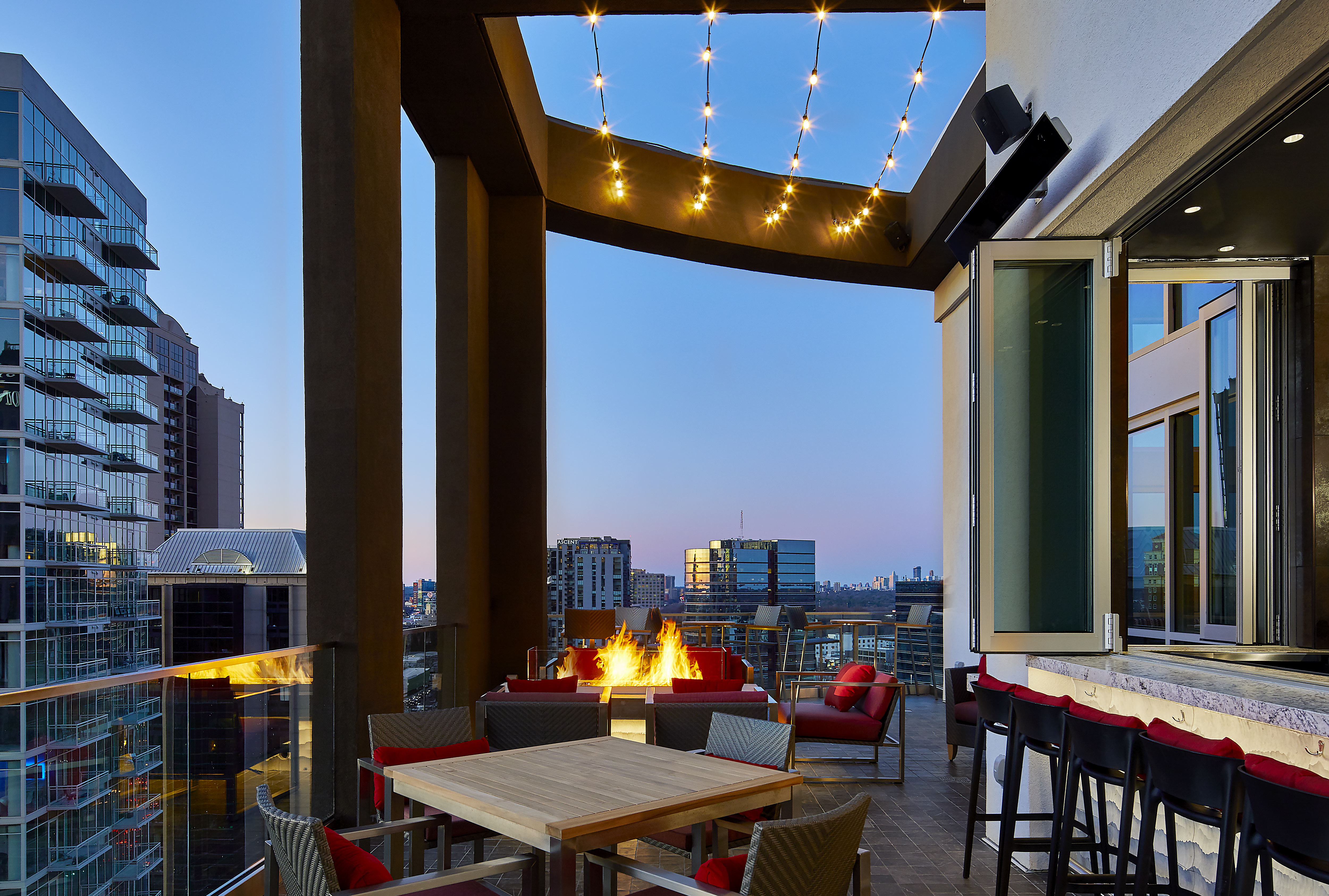 a terrace with tables, a fire pit and a view of skyline