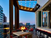 a terrace with tables, a fire pit and a view of skyline