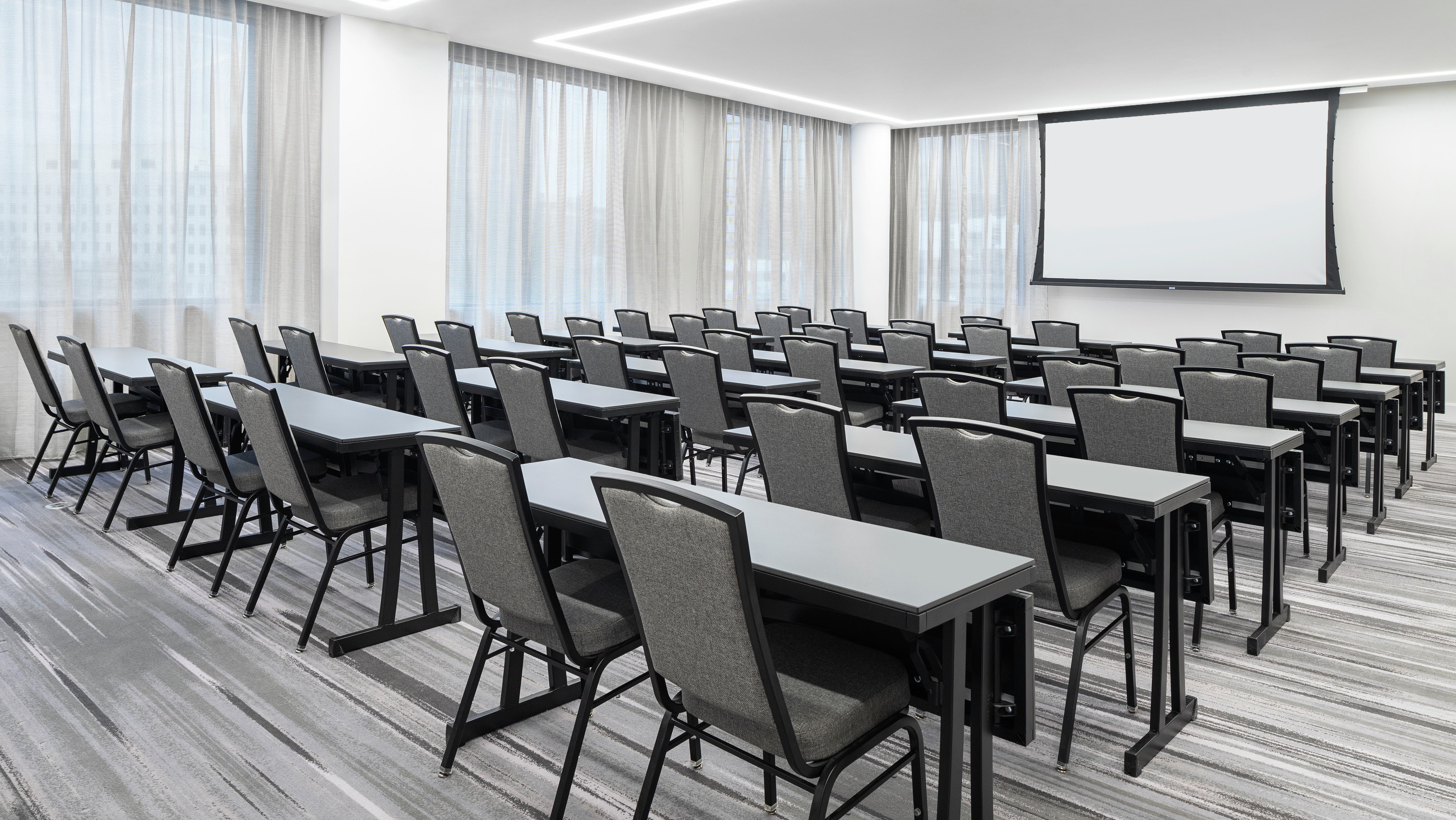 Meeting Room Set Up Classroom Style with Tables, Chairs, and Projector Screen