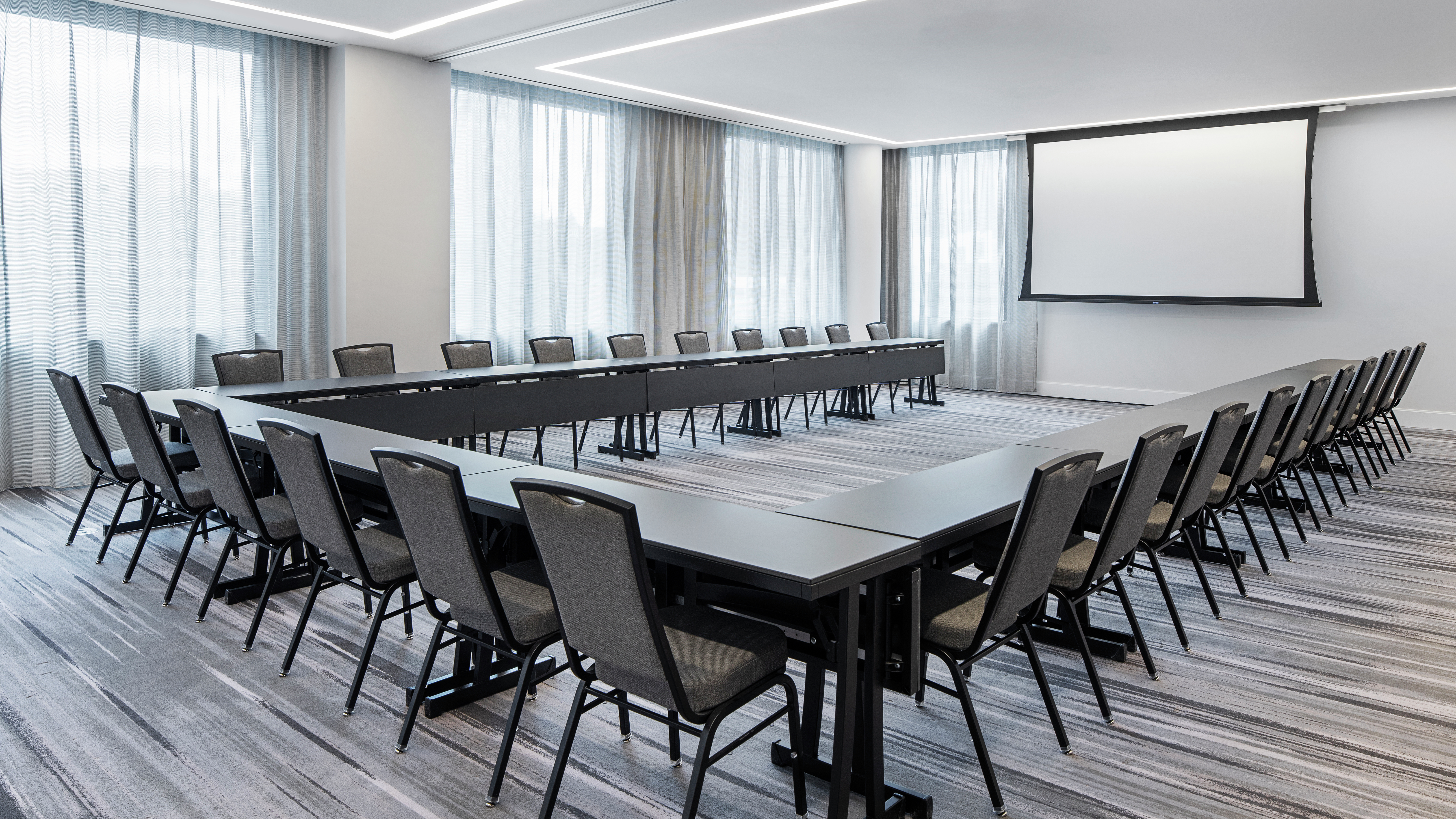 Meeting Space with U-Shaped Table Setup with Chairs and Projector Screen